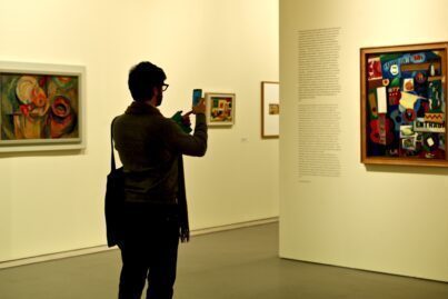 Man taking a picture of a painting in a museum