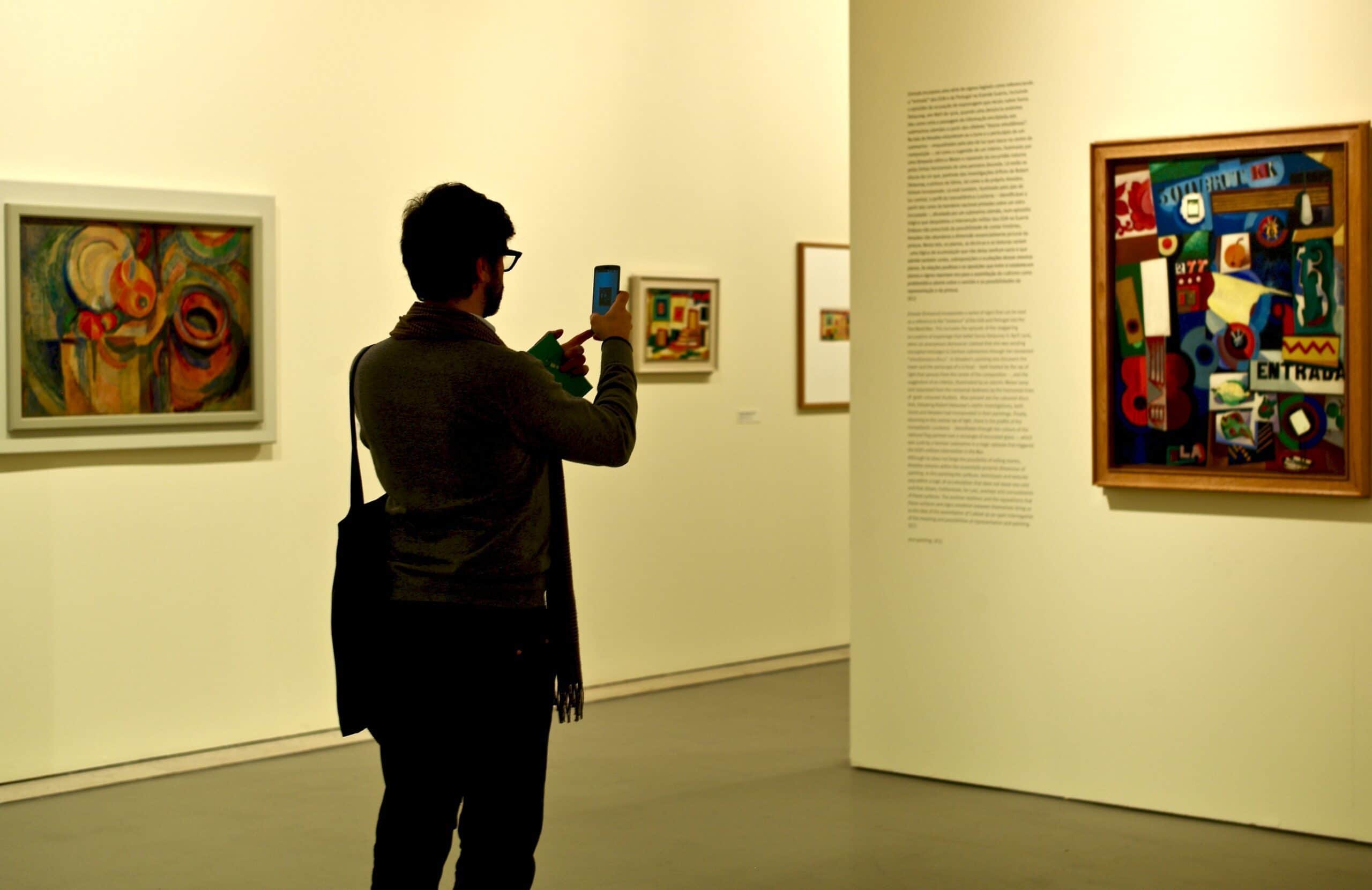 Homme prenant une photo d'une peinture dans un musée