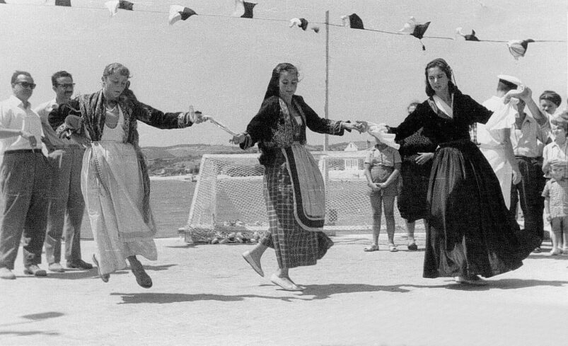 A black and white picture of three women dancing in Greek folk costume
